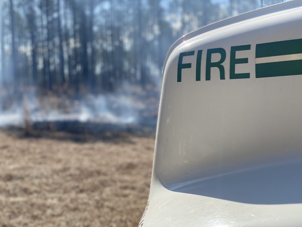 hood of wildland firefighting truck, with smoke in the background
