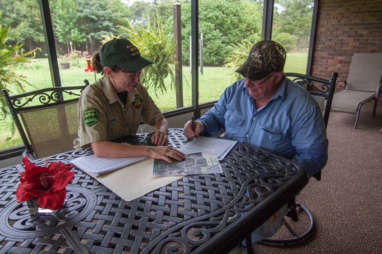 Man singing documents, being assisted by park ranger.