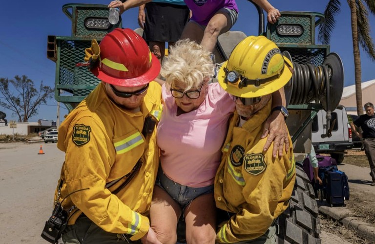 Two firefighters carrying woman.