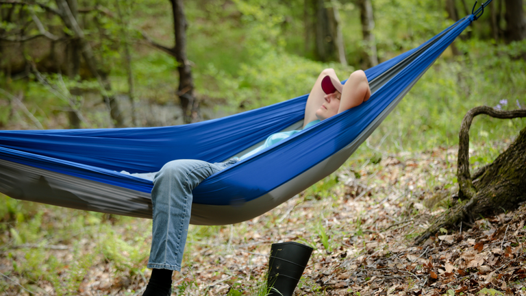 Person relaxing in a hammock in the woods