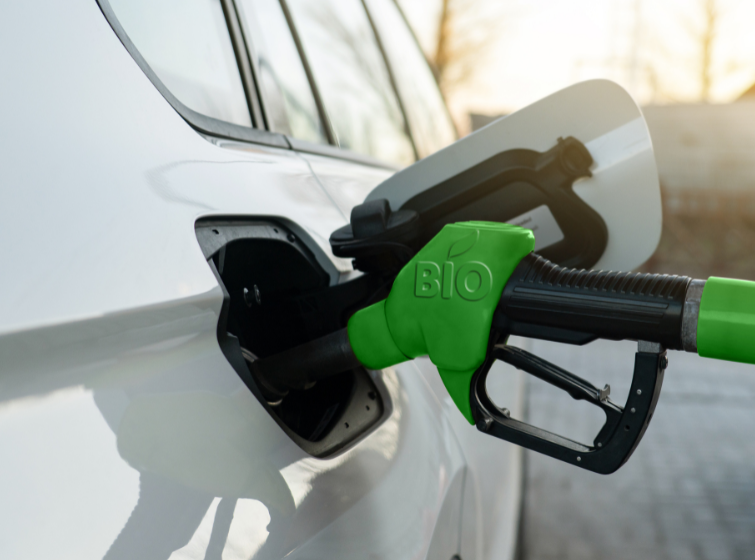 green gas pump with the label "BIO" on it, pumping into a white car