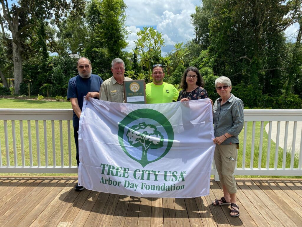 Group of people pose behind a large "Tree City USA" banner