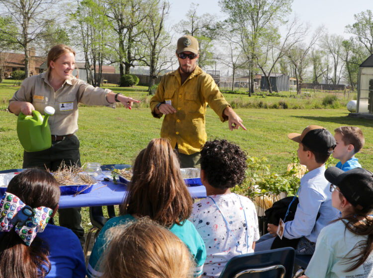 Forestry educator and wildland firefighter conduct conservation education training outdoors for a group of children