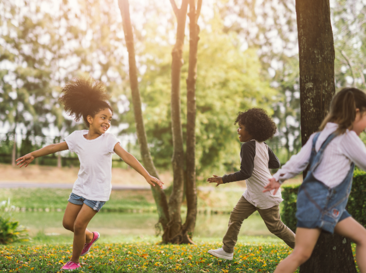 Group of children playing and running in a natural area of a local park.