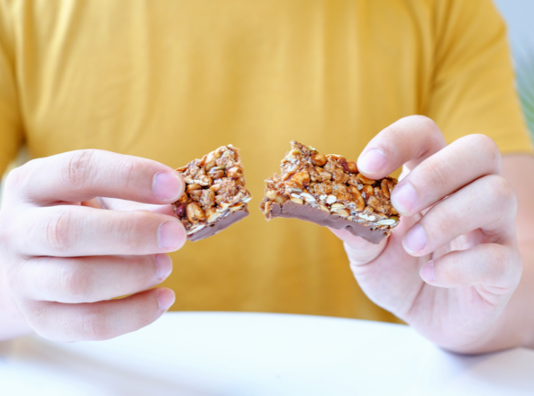 closeup of a person's hands with holding two halves of a granola bar in each hand.  