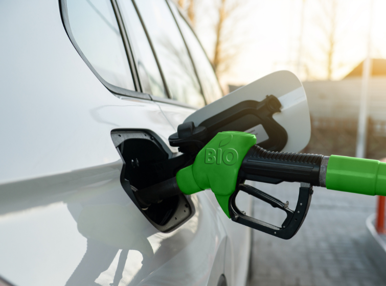 closeup of a green gas pump that says "biofuel" filling up a car's gas tank