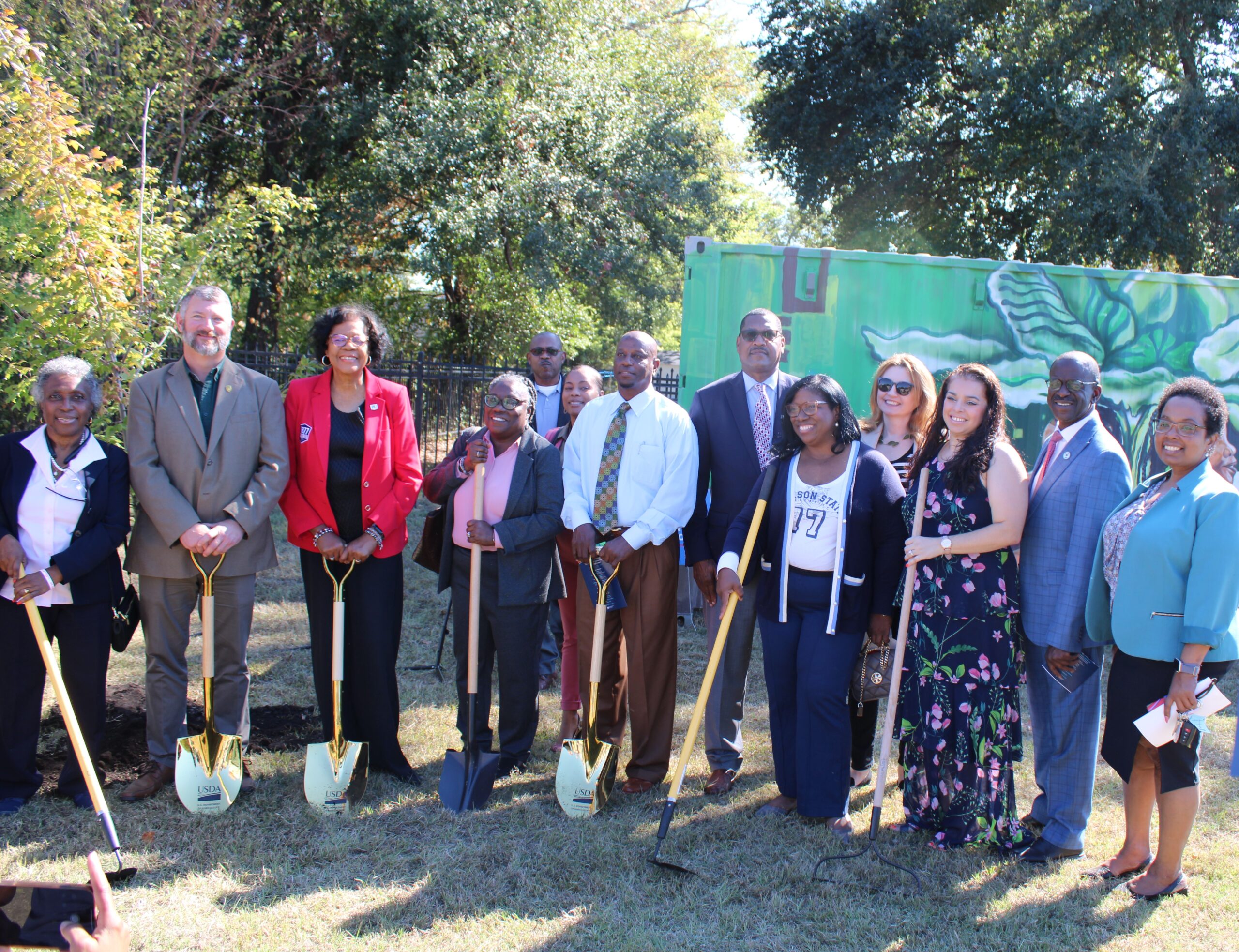 Group poses with shovels at a tree planting ceremony