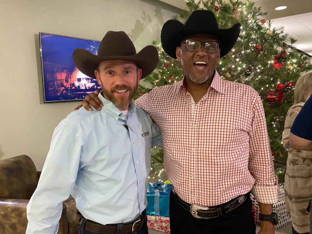 Two men wearing cowboy hats pose in front of a Christmas Tree (Wes Moorehead and Al Davis)
