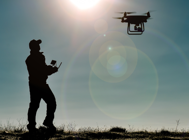 silhouette of a man operating a drone in an open field