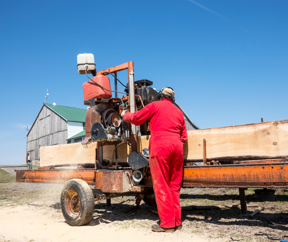 Man in a jumpsuit operates a mobile sawmill