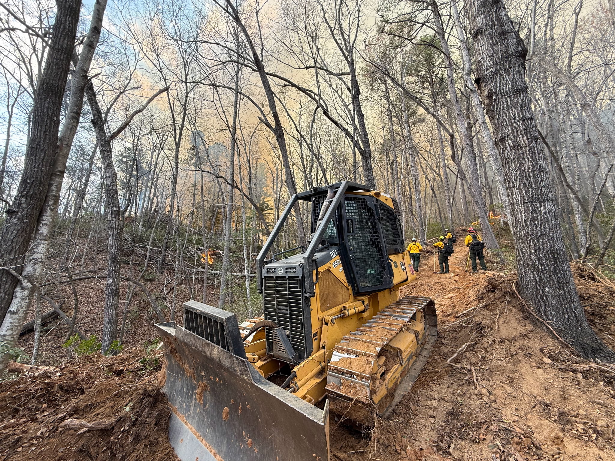 Bulldozer on a fireline with wildland firefighters working in the background