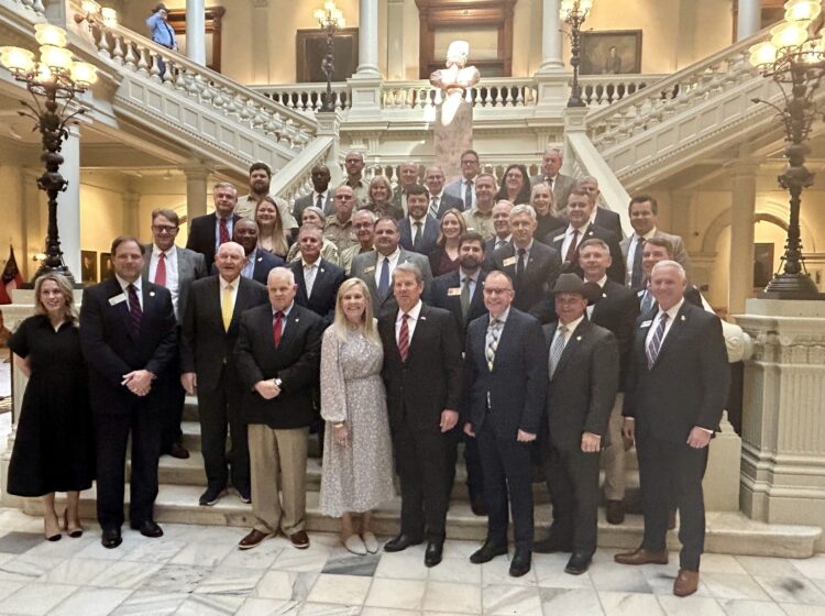 Group of individuals standing on the steps inside of the Georgia State Capitol