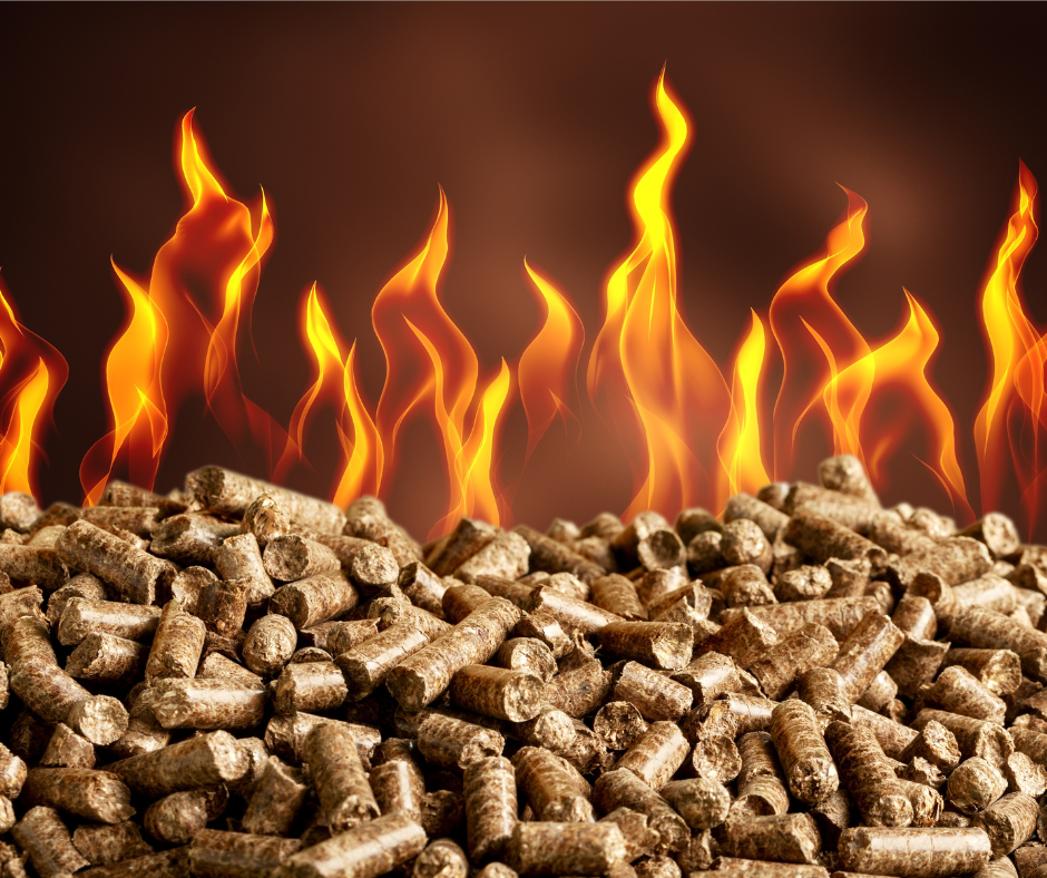 Close-up of a large pile of compressed wood pellets with bright orange flames rising above them against a dark background. The image symbolizes woody biomass as a renewable energy source and its role in producing renewable fuels.